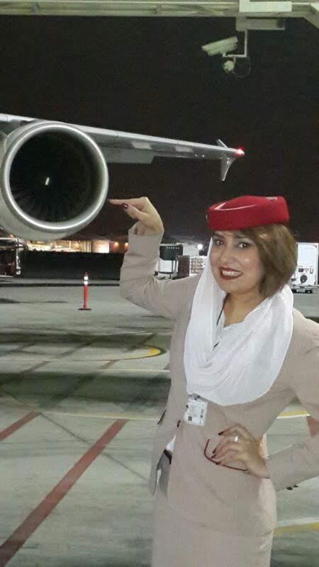 Bineeta in her cabin crew uniform beside an aircraft engine at night